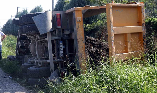 Toprak yüklü kamyon yol kenarına devrildi